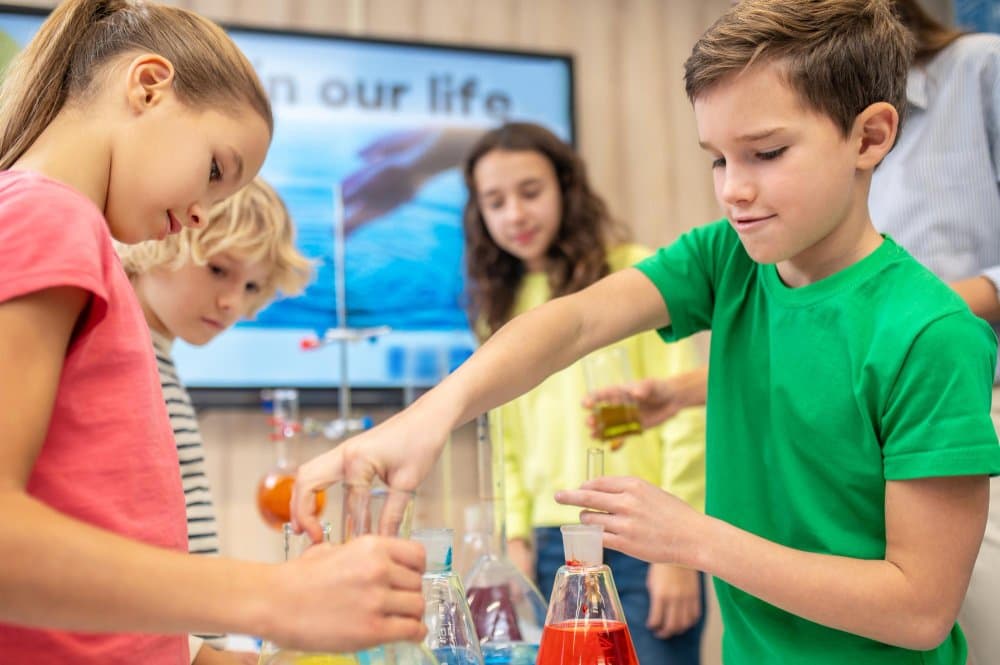 Children in a science class conducting an experiment with colorful liquids in beakers.