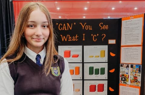 Student in uniform with her project on Vitamin C (C-themed title).